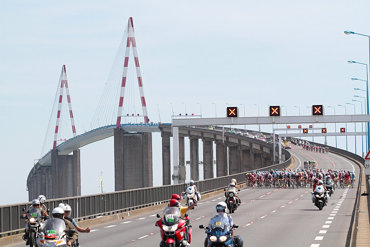横風の吹くサンナゼール橋を通過したプロトン