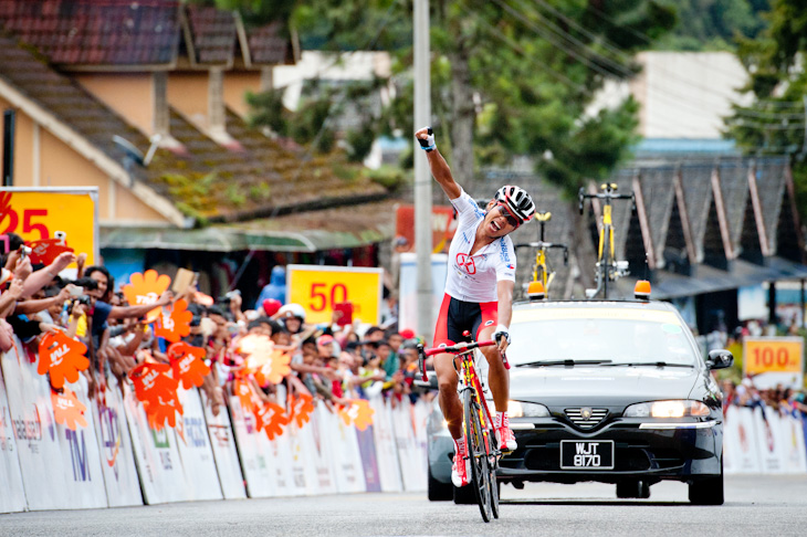 第3ステージ 片手を突き上げてゴールするワン・メイイン(中国、ハンシャンサイクリング)