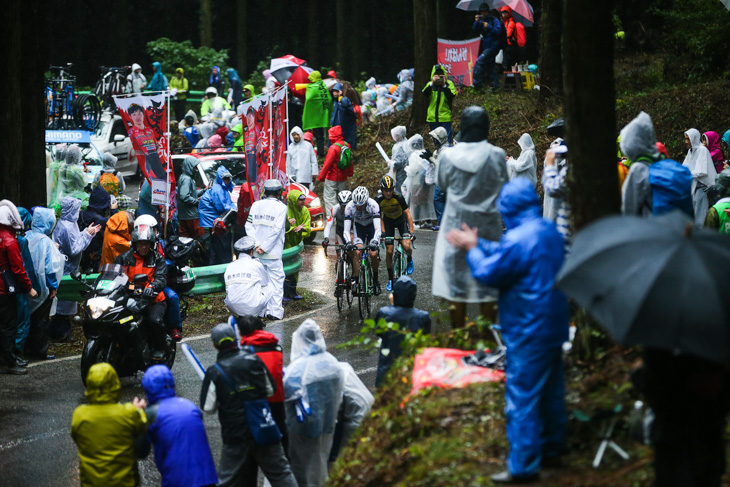 雨具に身を包んだ観客を縫って進むトマ・ルバ(フランス、キナンサイクリング)ら