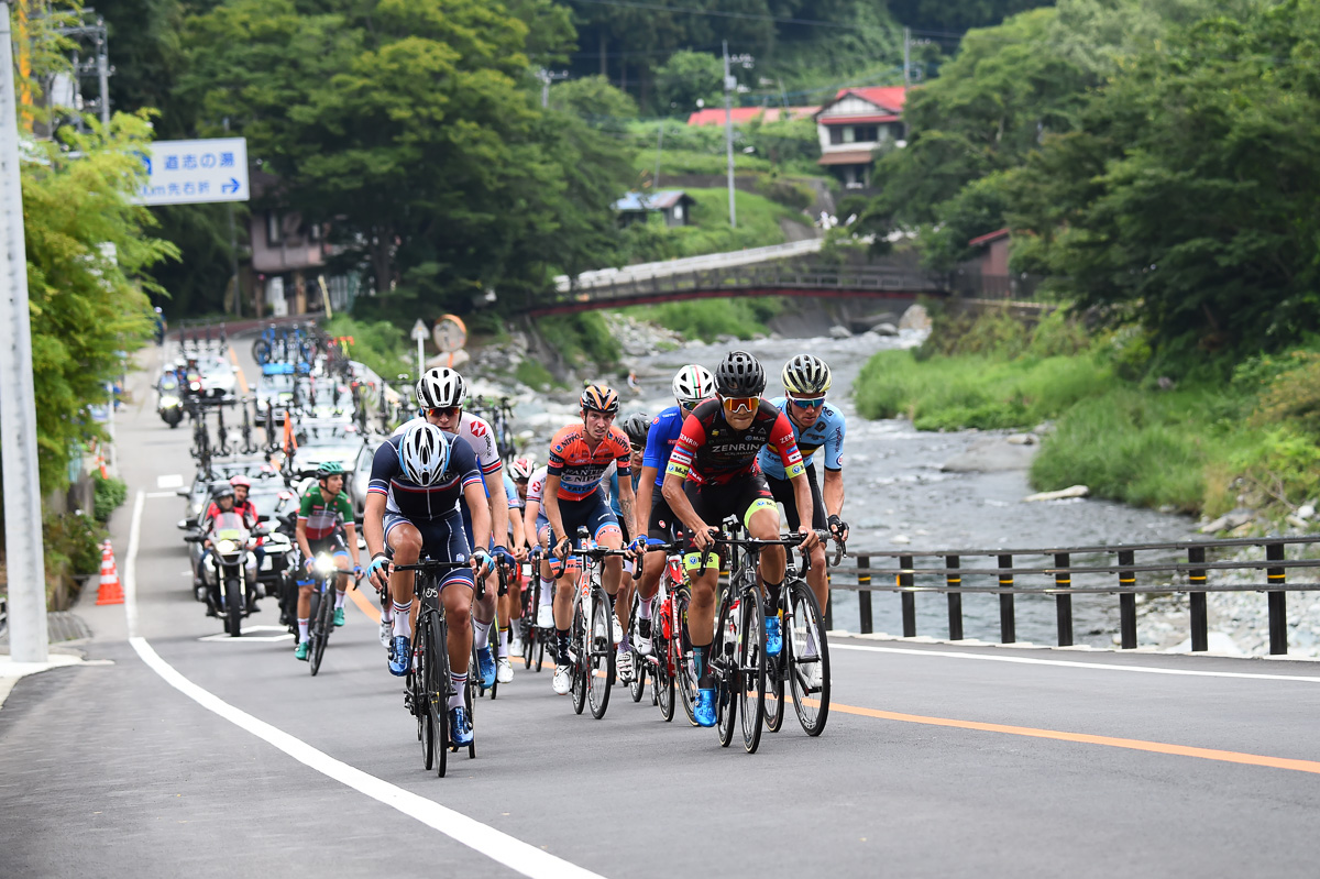 横塚浩平(チーム右京)を先頭に道志川沿いを行く19名の追走集団
