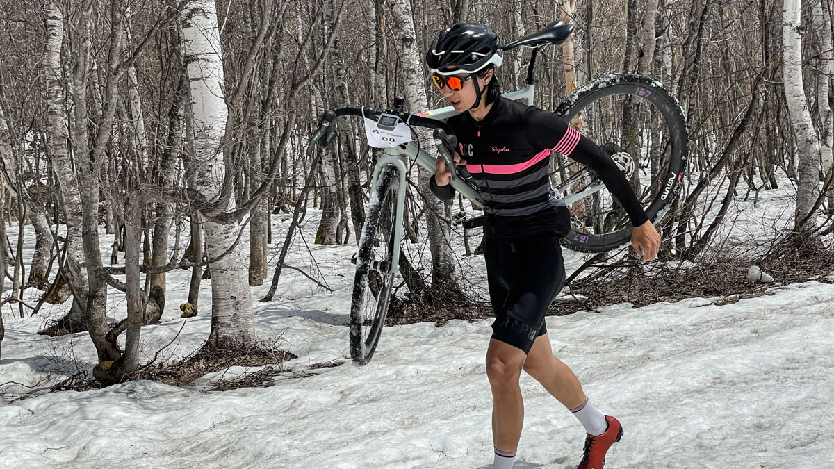 バイクを担いで雪原を行くトップの吉川大地選手(Rapha Cycle Club)