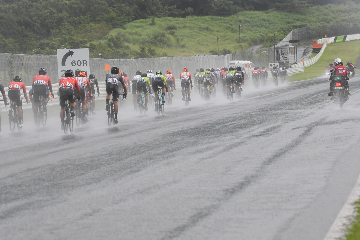 3周目から降り出した雨 水しぶきをあげてダウンヒルしていく集団